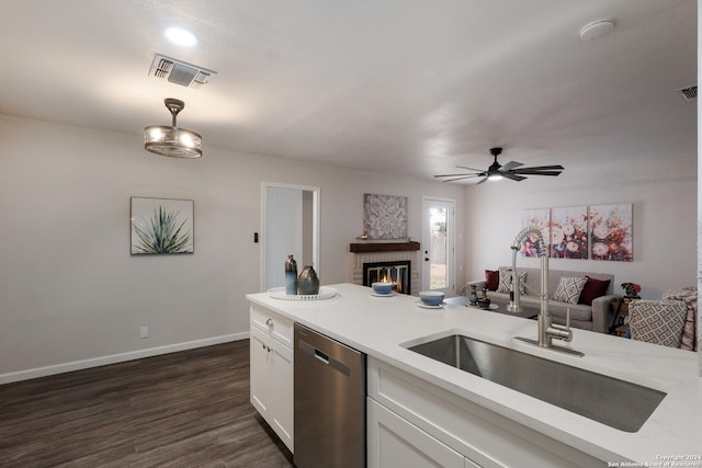 kitchen with stainless steel dishwasher, ceiling fan, dark wood-type flooring, a fireplace, and white cabinetry