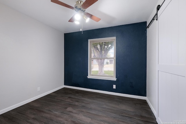 unfurnished room with dark hardwood / wood-style flooring, a barn door, and ceiling fan