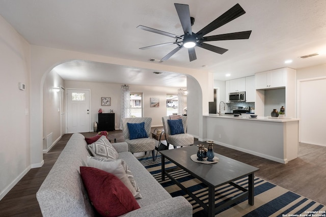 living room featuring dark hardwood / wood-style flooring, ceiling fan, and sink