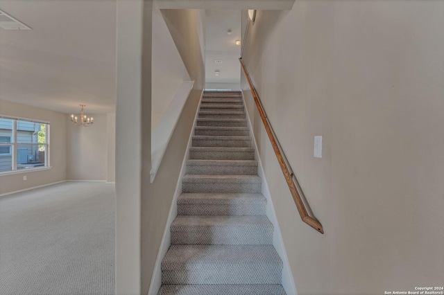 staircase with carpet and a notable chandelier