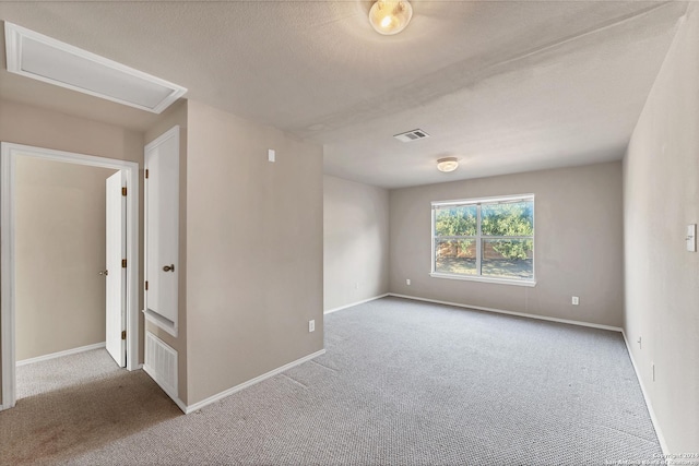 spare room with a textured ceiling and light carpet