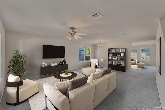 carpeted living room featuring ceiling fan with notable chandelier