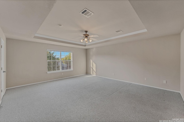 carpeted empty room with a tray ceiling and ceiling fan