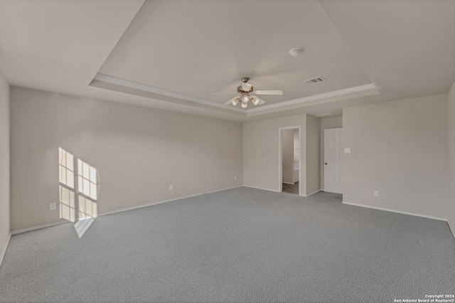 carpeted spare room with ceiling fan and a raised ceiling