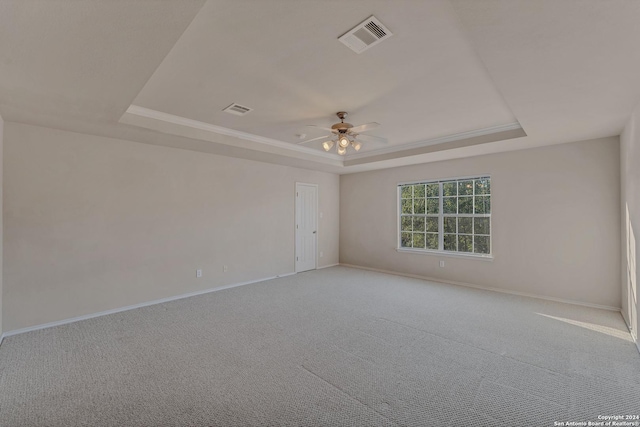 unfurnished room with a tray ceiling, light carpet, and ceiling fan