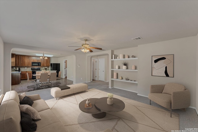 carpeted living room with ceiling fan and built in shelves