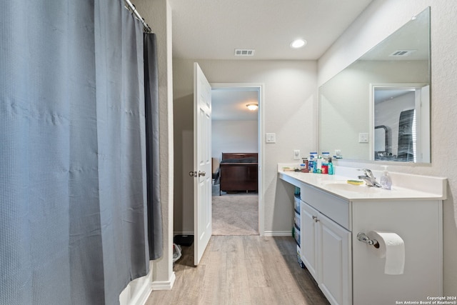 bathroom featuring hardwood / wood-style flooring, vanity, and walk in shower