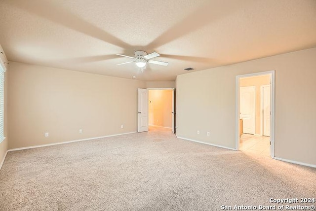 spare room featuring ceiling fan, light colored carpet, and a textured ceiling