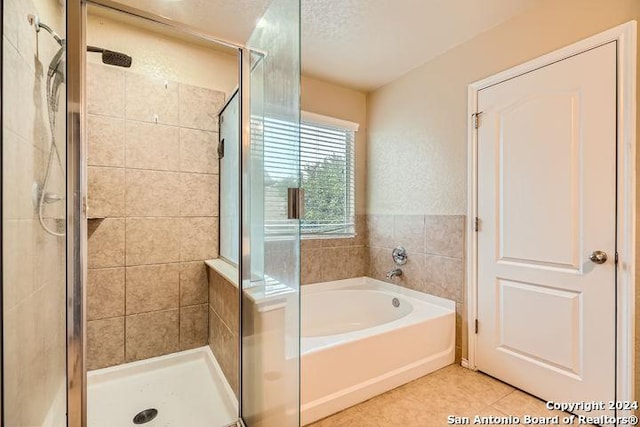 bathroom featuring plus walk in shower, a textured ceiling, and tile patterned floors