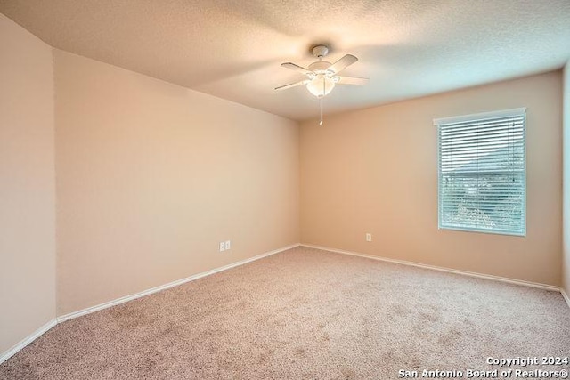 carpeted spare room featuring a textured ceiling and ceiling fan