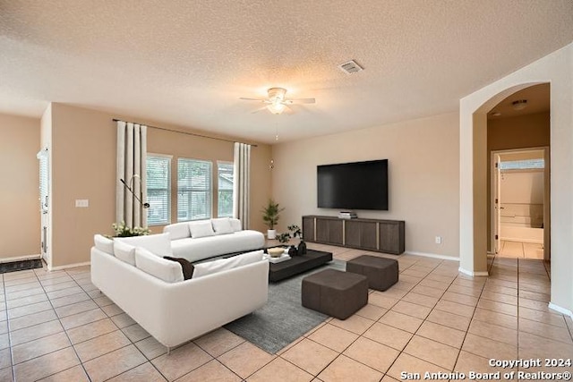 living room with ceiling fan, light tile patterned floors, and a textured ceiling