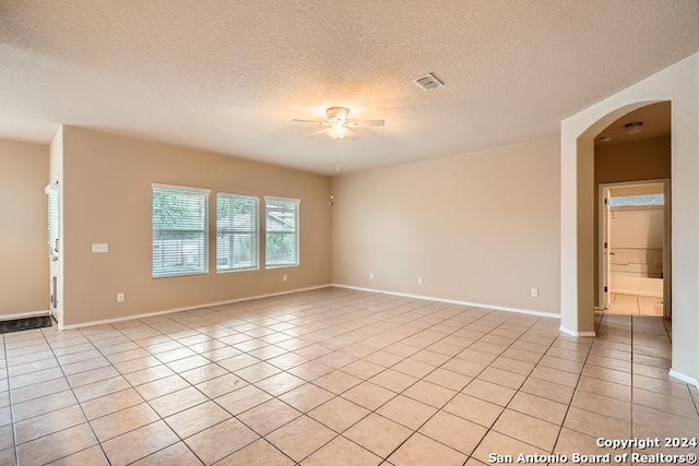 empty room featuring ceiling fan, light tile patterned flooring, and a textured ceiling