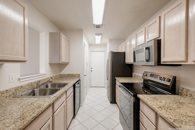 kitchen with sink, light tile patterned floors, light brown cabinetry, appliances with stainless steel finishes, and light stone counters