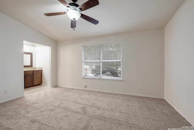 unfurnished bedroom featuring light carpet, ensuite bathroom, ceiling fan, and lofted ceiling