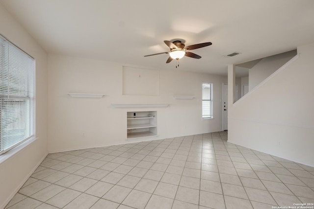 unfurnished living room featuring ceiling fan, built in features, and light tile patterned floors