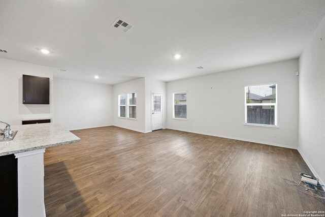 unfurnished living room featuring hardwood / wood-style flooring and sink