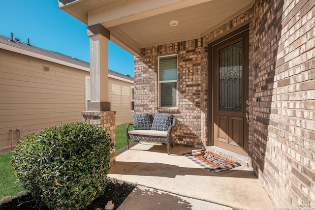 entrance to property with brick siding and a porch