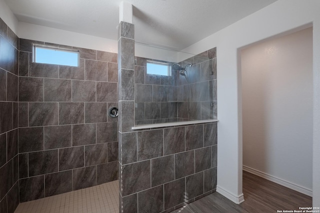 bathroom with a tile shower, a wealth of natural light, and hardwood / wood-style flooring