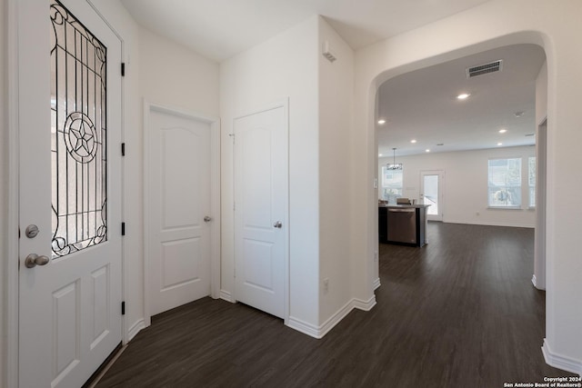 foyer with visible vents, baseboards, recessed lighting, arched walkways, and dark wood-style flooring