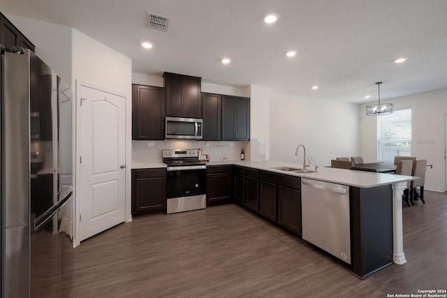 kitchen featuring kitchen peninsula, stainless steel appliances, hanging light fixtures, and sink