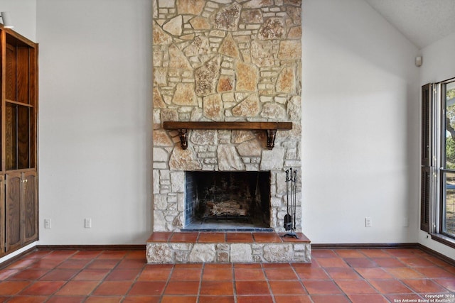 unfurnished living room featuring tile patterned floors, a stone fireplace, a wealth of natural light, and vaulted ceiling