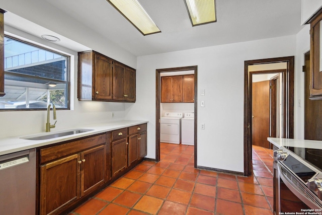 kitchen featuring dark tile patterned floors, sink, appliances with stainless steel finishes, and washing machine and clothes dryer