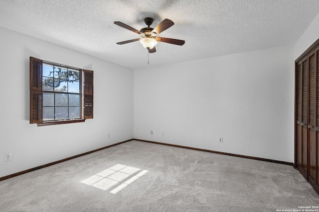 unfurnished bedroom with ceiling fan, a textured ceiling, light carpet, and a closet