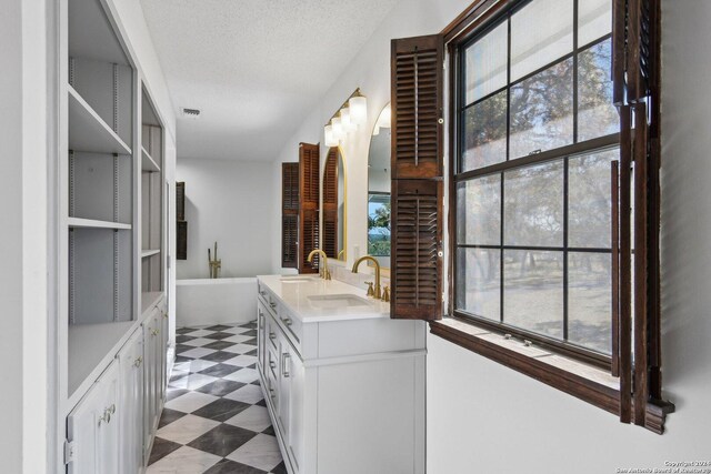 bathroom featuring vanity, a textured ceiling, and a tub