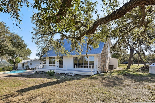 rear view of house with a swimming pool side deck, a yard, and central AC