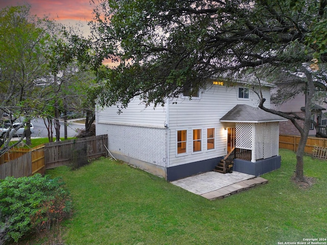 back house at dusk featuring a yard