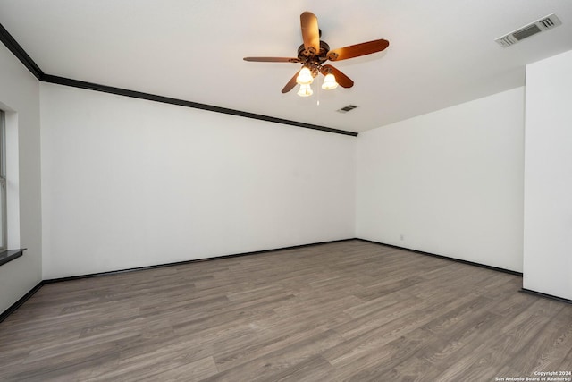 empty room featuring hardwood / wood-style flooring, ceiling fan, and crown molding