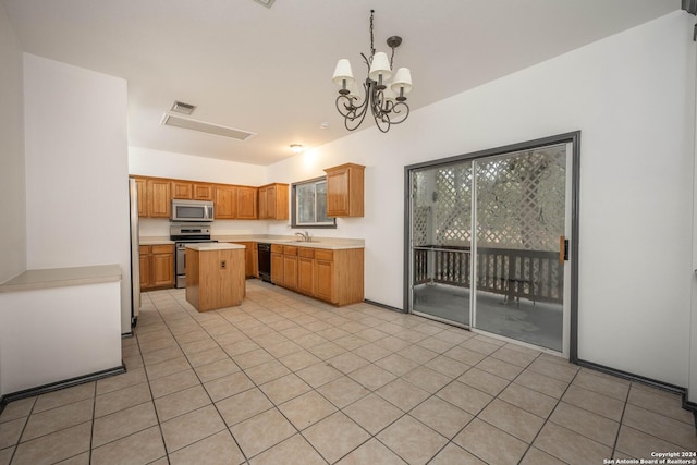 kitchen with sink, decorative light fixtures, a kitchen island, stainless steel appliances, and a chandelier