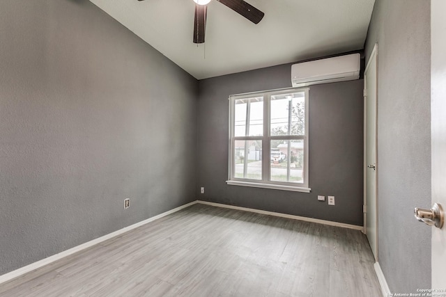 empty room featuring a wall unit AC, ceiling fan, and light hardwood / wood-style flooring