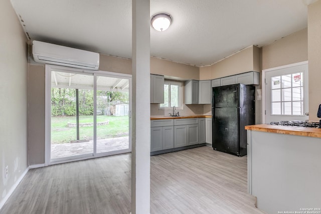 kitchen with black refrigerator, a wall mounted AC, a wealth of natural light, and butcher block counters