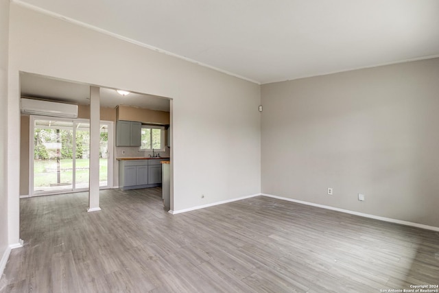 unfurnished room featuring hardwood / wood-style floors, crown molding, and a wall unit AC