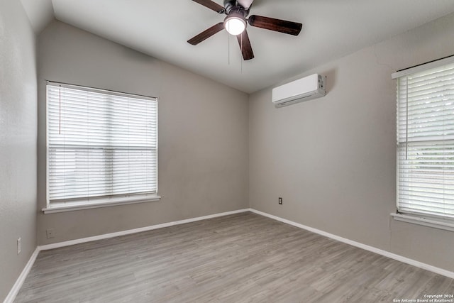 spare room featuring an AC wall unit, a wealth of natural light, and light wood-type flooring