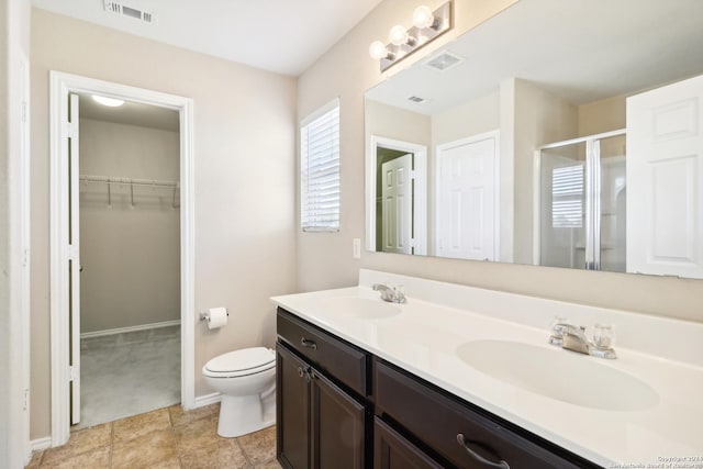 bathroom featuring toilet, vanity, tile patterned floors, and a shower with door