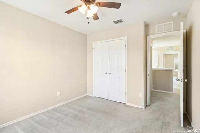 unfurnished bedroom featuring ceiling fan, a closet, and light carpet