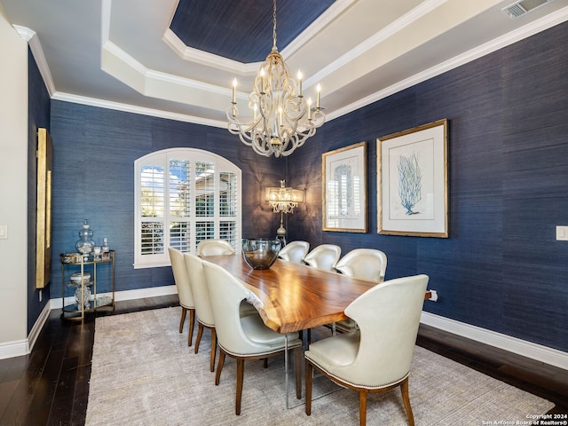 dining space featuring hardwood / wood-style floors, a notable chandelier, a raised ceiling, and ornamental molding