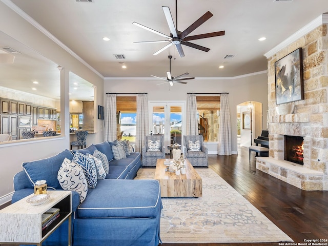 living room with a fireplace, crown molding, ceiling fan, and dark wood-type flooring