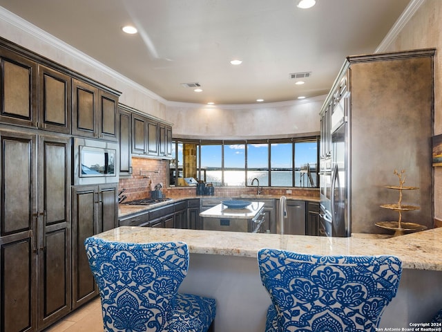 kitchen with crown molding, light stone counters, kitchen peninsula, and stainless steel appliances