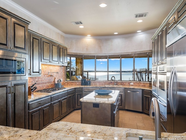 kitchen featuring built in appliances, a water view, light stone counters, and tasteful backsplash