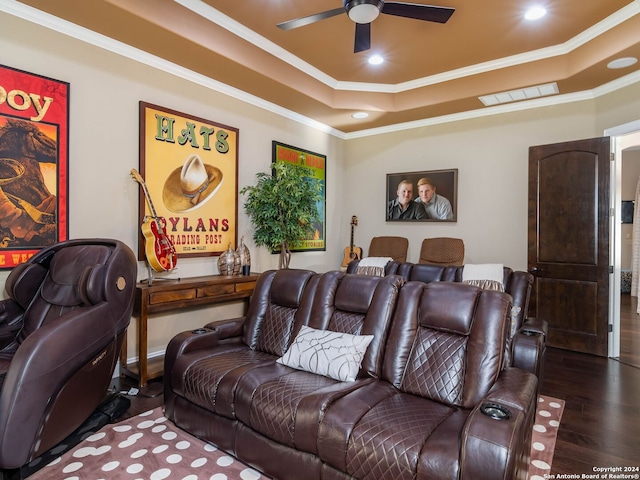 home theater with wood-type flooring, a raised ceiling, and ornamental molding