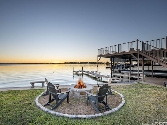 dock area featuring a water view, a fire pit, and a lawn