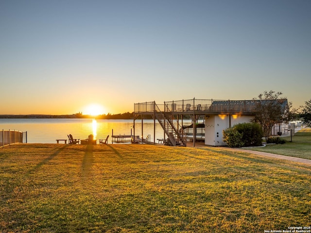 view of dock with a yard and a water view