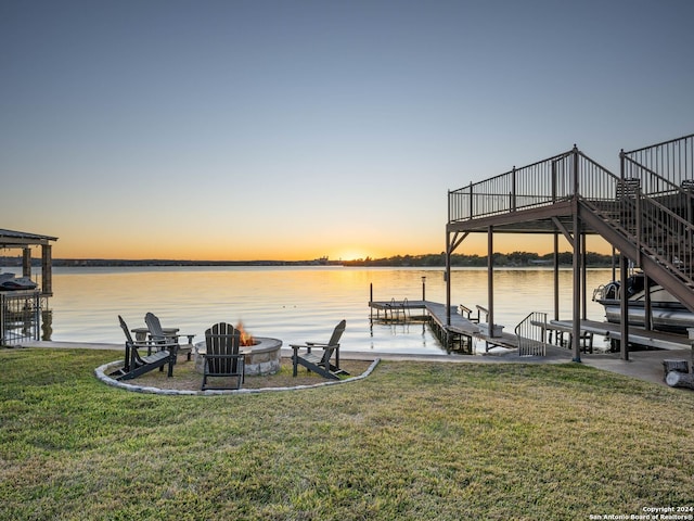 dock area featuring a fire pit, a water view, and a yard