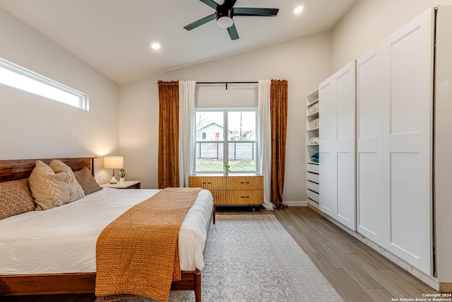 bedroom with ceiling fan, lofted ceiling, light wood-type flooring, and multiple windows