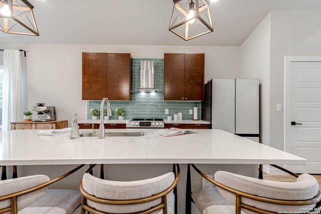 kitchen featuring pendant lighting, wall chimney exhaust hood, stainless steel stove, and tasteful backsplash