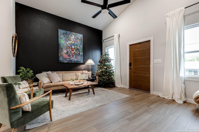 living room featuring ceiling fan, light hardwood / wood-style floors, and lofted ceiling