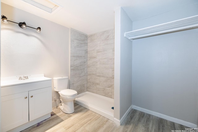 bathroom featuring hardwood / wood-style floors, vanity, toilet, and a tile shower